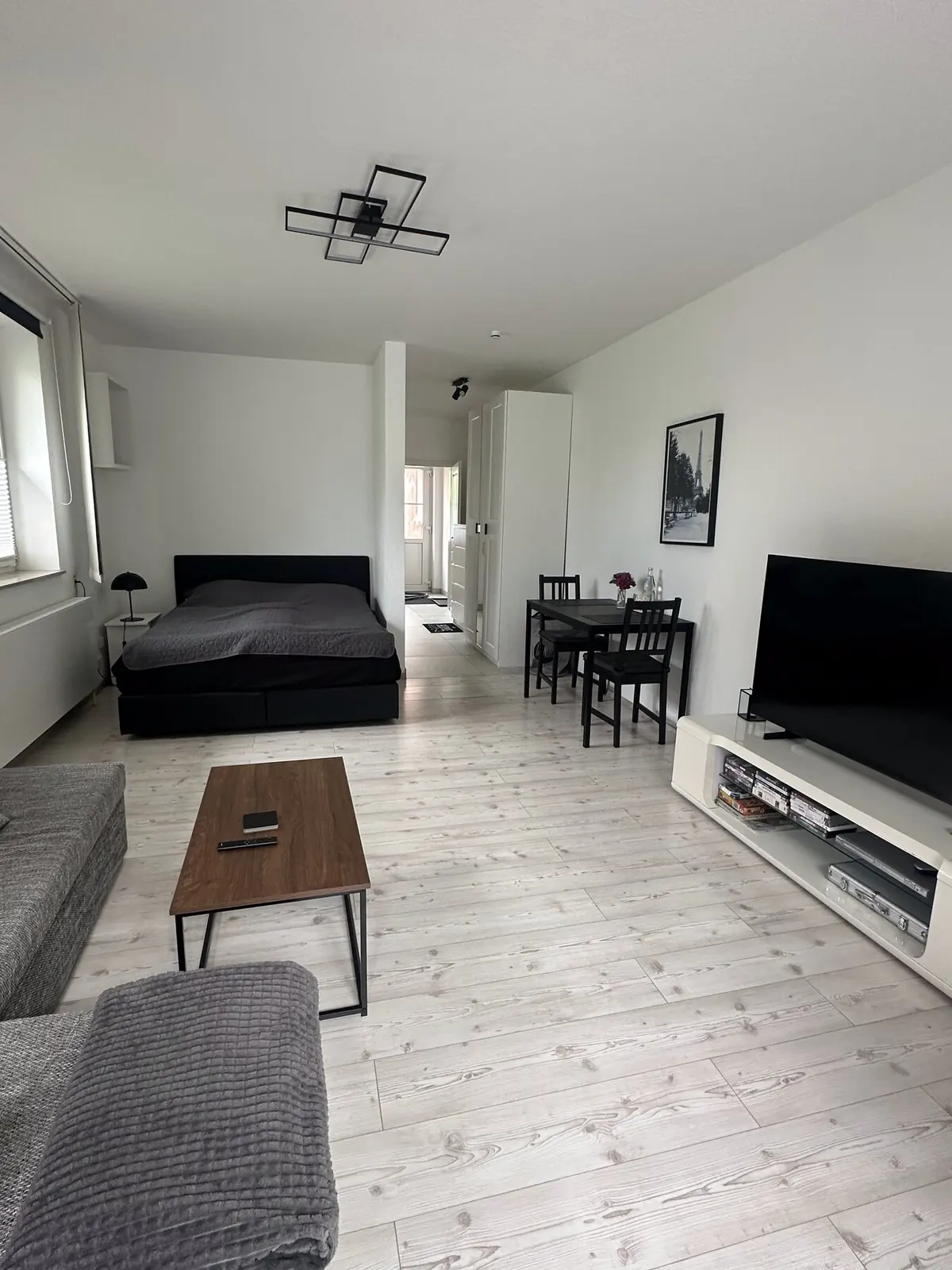 Heller Wohnraum mit Sofaecke, Esstisch und Schlafbereich